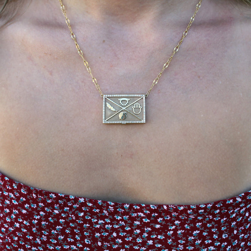 14k solid yellow gold Marqué Hieroglyphic locket with genuine conflict-free white diamonds and embellished with four hieroglyphics symbolizing beauty, trust, freedom, and good fortune.